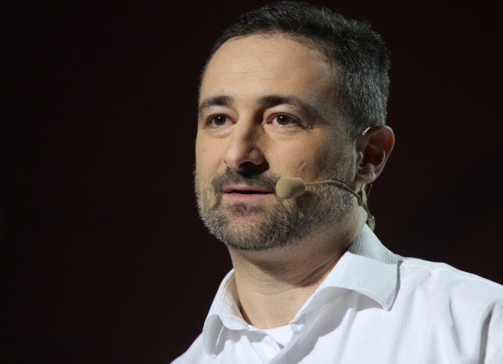 A man in a white shirt with a microphone.