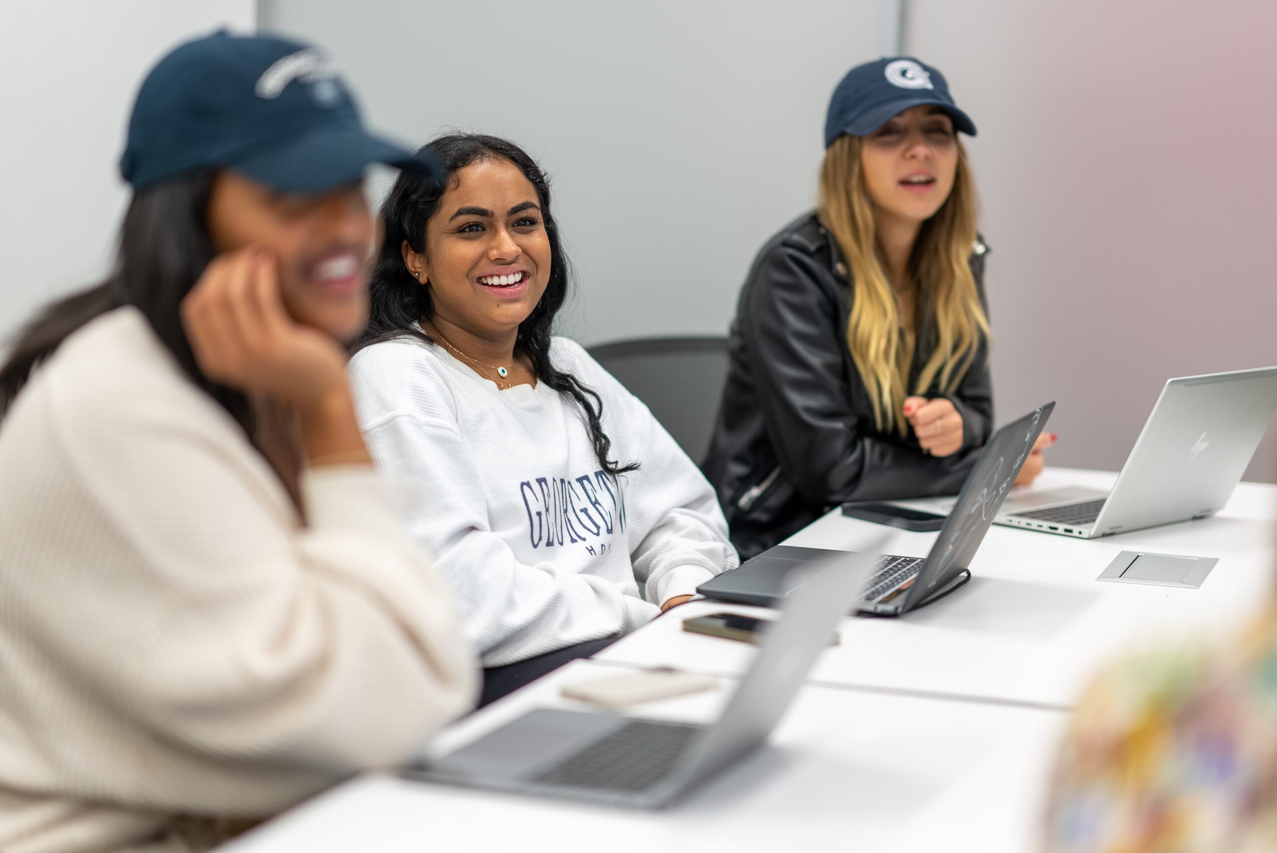 Three women sitting at a table with laptops.