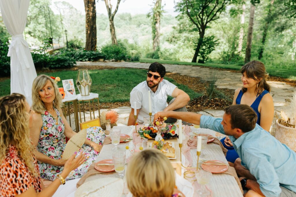 A group of people sitting around a table in a garden.