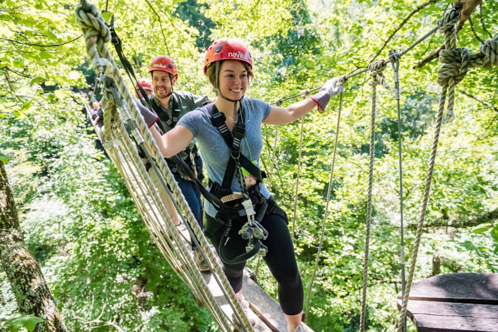 A group of people on a rope bridge in the woods.